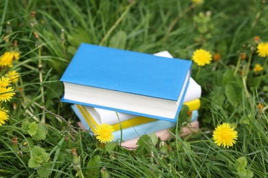 Photo of Stacked books on green grass outdoors, closeup
