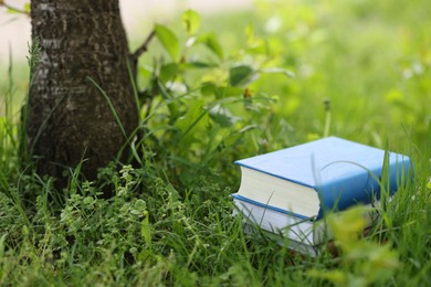 Photo of Stacked books on green grass outdoors,. Space for text