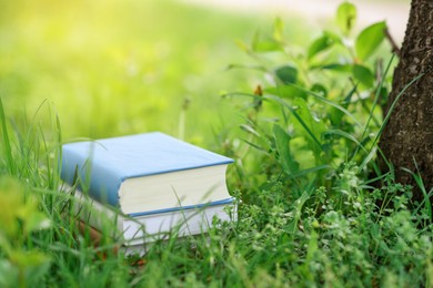 Photo of Stacked books on green grass outdoors,. Space for text