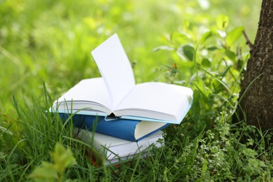 Photo of Different stacked books on green grass outdoors