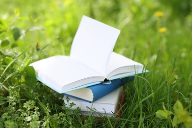 Photo of Different stacked books on green grass outdoors
