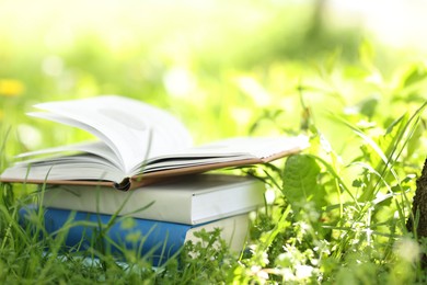 Photo of Different stacked books on green grass outdoors