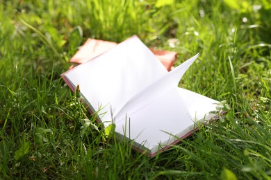 Photo of Books on green grass outdoors, closeup view
