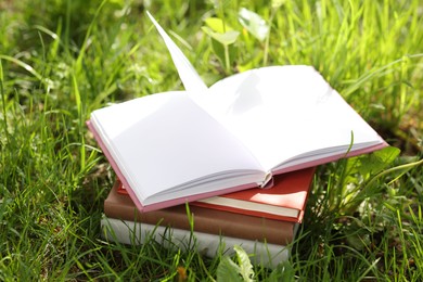 Photo of Different stacked books on green grass outdoors