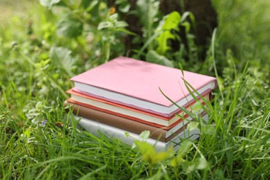 Photo of Stacked books on green grass outdoors, closeup