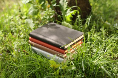 Photo of Different stacked books on green grass outdoors