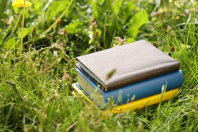 Photo of Different stacked books on green grass outdoors