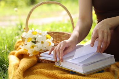 Photo of Woman reading book on blanket outdoors, closeup