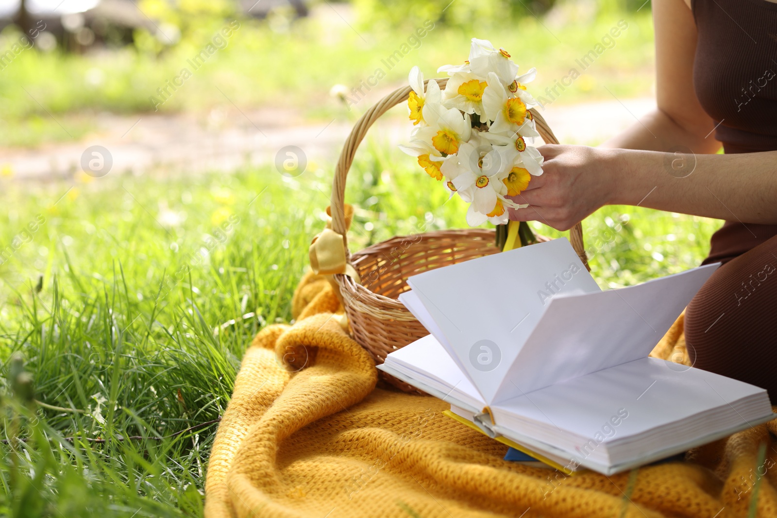 Woman reading book on blanket outdoors, closeup Photo of Woman reading book on blanket outdoors, closeup