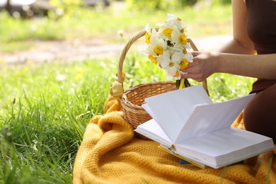 Photo of Woman reading book on blanket outdoors, closeup