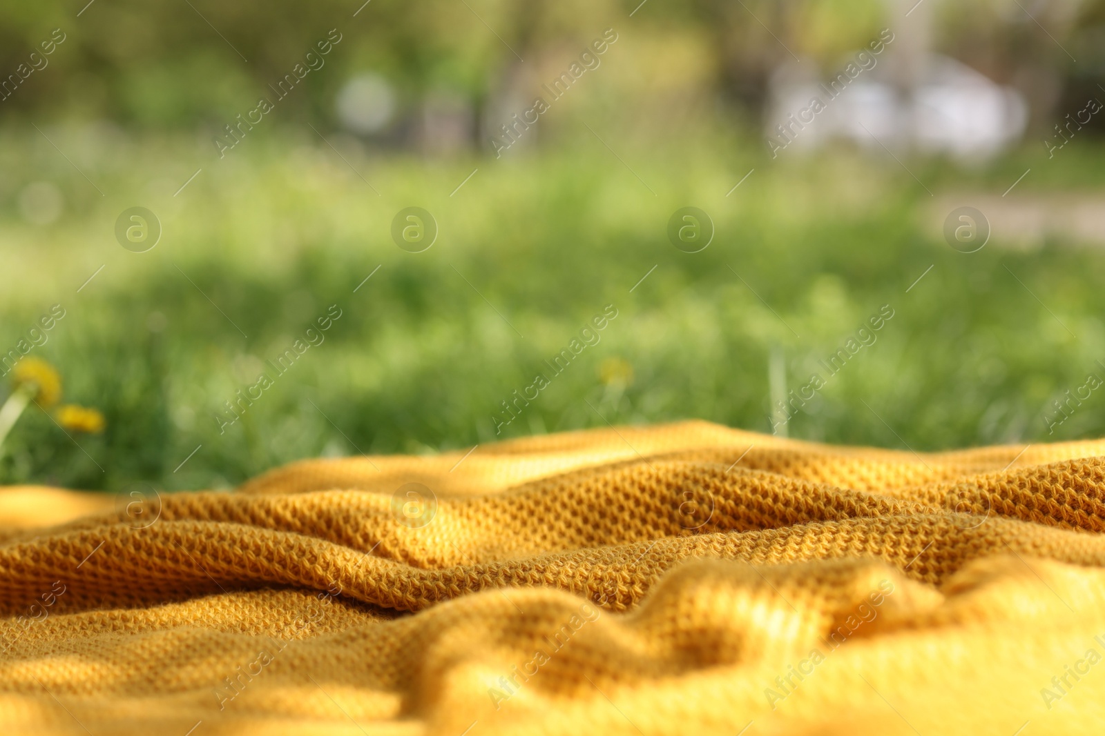 Orange blanket for picnic on green grass outdoors, closeup Photo of Orange blanket for picnic on green grass outdoors, closeup