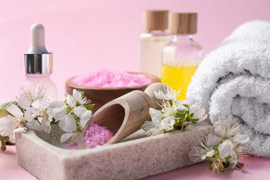 Photo of Spa composition with cosmetic products and beautiful flowers on pink background, closeup