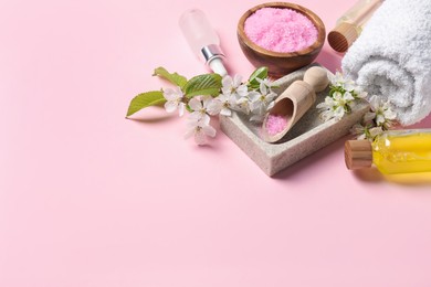 Photo of Spa composition with cosmetic products and beautiful flowers on pink background. Space for text