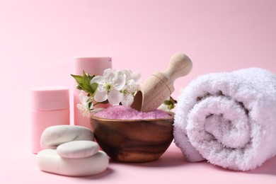 Photo of Spa composition with cosmetic products, pebble stones and beautiful flowers on pink background, closeup