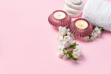 Photo of Spa composition with burning candles, pebble stones and twigs with beautiful flowers on pink background. Space for text