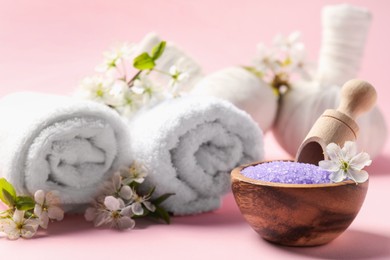 Photo of Spa composition with sea salt and beautiful flowers on pink background, closeup