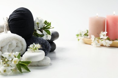 Photo of Spa composition with pebble stones, beautiful flowers and burning candles on white background, selective focus