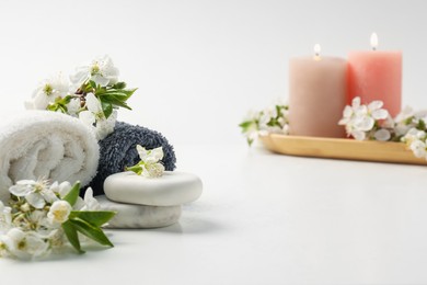 Photo of Spa composition with pebble stones, beautiful flowers and burning candles on white background, selective focus