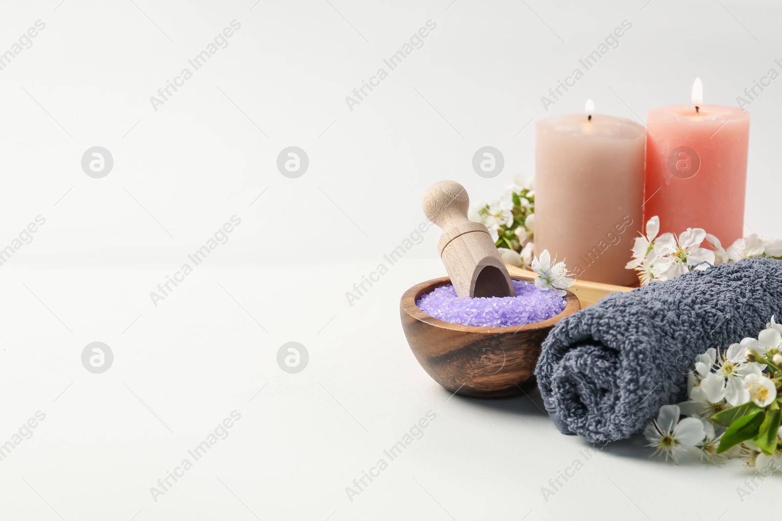 Spa composition with cosmetic products, beautiful flowers and burning candles on white table, closeup. Space for text Photo of Spa composition with cosmetic products, beautiful flowers and burning candles on white table, closeup. Space for text