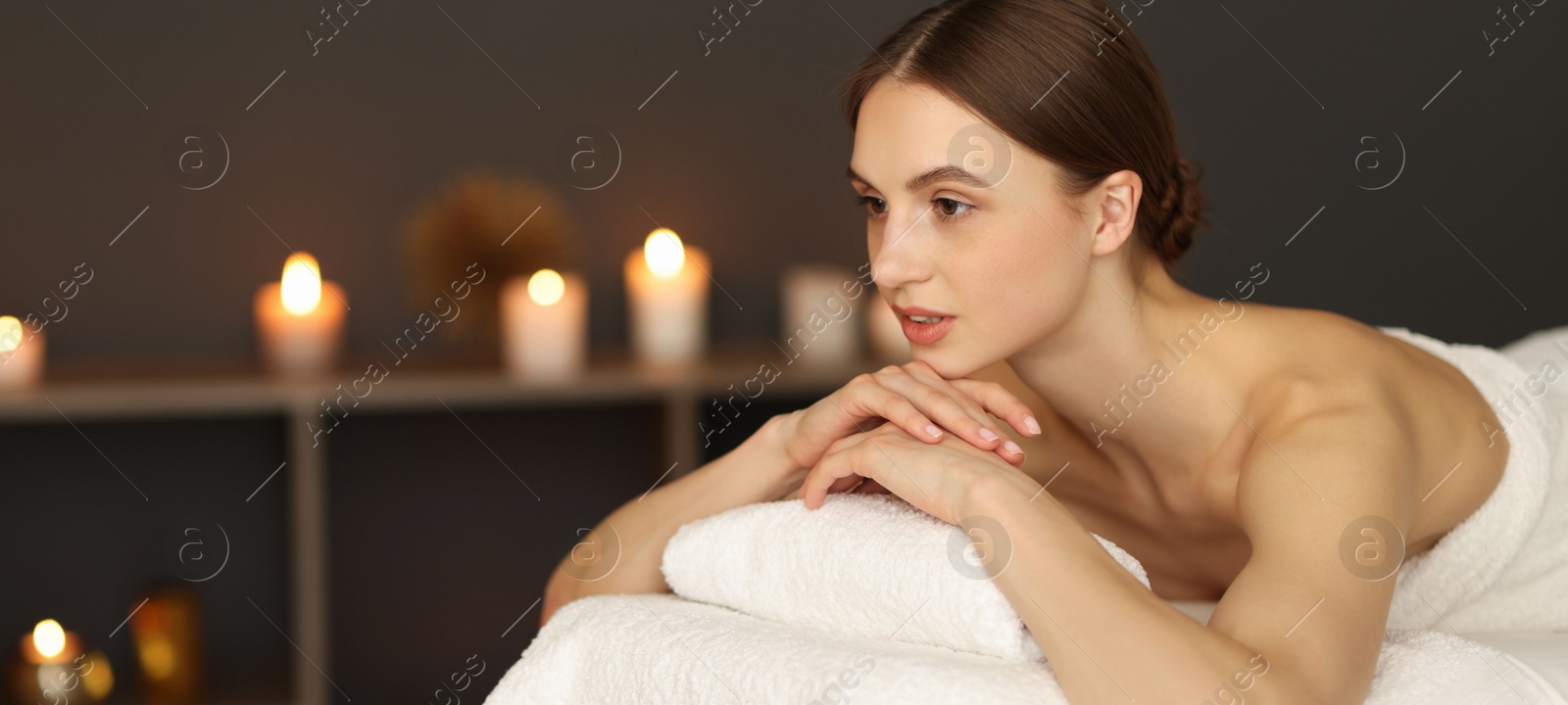 Beautiful woman relaxing on massage couch in spa salon. Space for text Photo of Beautiful woman relaxing on massage couch in spa salon. Space for text