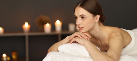 Photo of Beautiful woman relaxing on massage couch in spa salon. Space for text