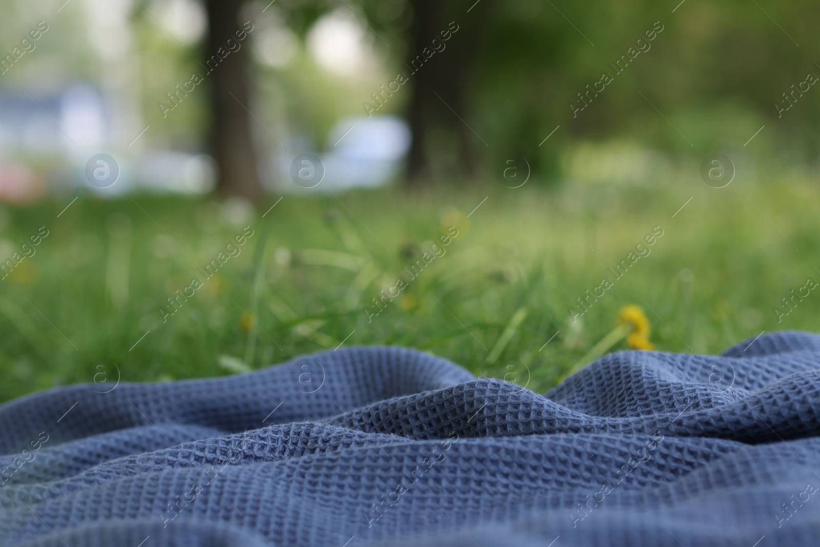 Blue blanket for picnic on green grass outdoors, closeup Photo of Blue blanket for picnic on green grass outdoors, closeup