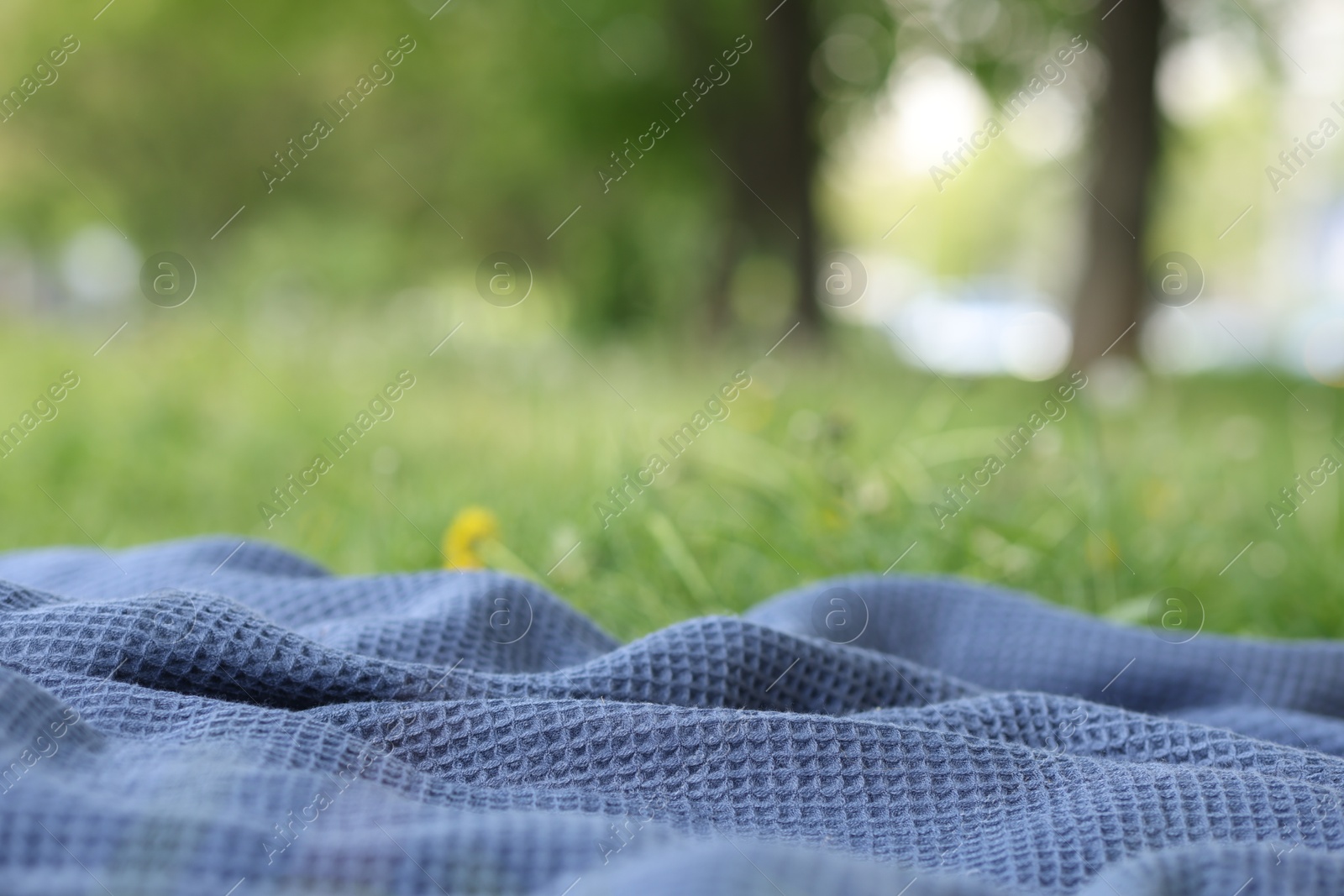 Blue blanket for picnic on green grass outdoors, closeup Photo of Blue blanket for picnic on green grass outdoors, closeup