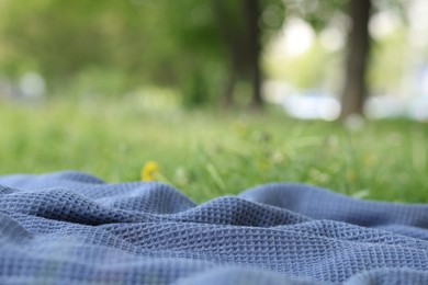 Photo of Blue blanket for picnic on green grass outdoors, closeup