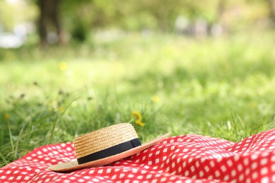 Photo of Straw hat and blanket on green grass outdoors Space for text