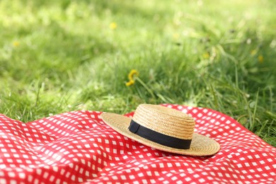 Photo of Straw hat and blanket on green grass outdoors