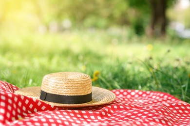 Photo of Straw hat and blanket on green grass outdoors. Space for text