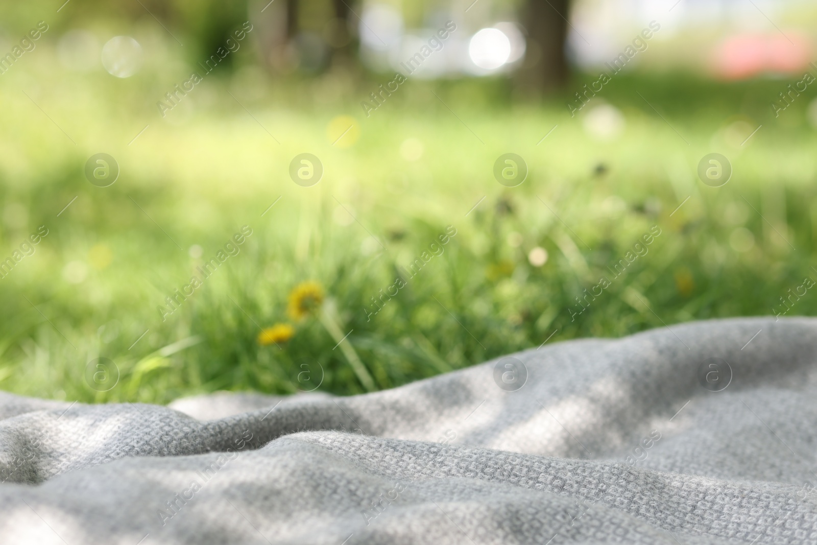 Light grey blanket for picnic on green grass outdoors, closeup Photo of Light grey blanket for picnic on green grass outdoors, closeup