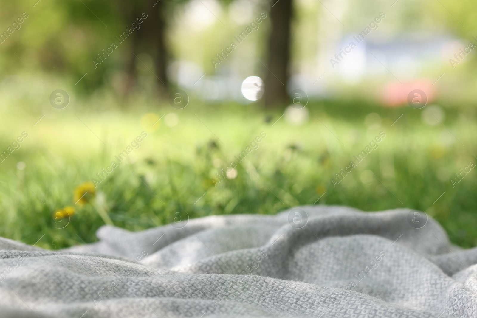 Light grey blanket for picnic on green grass outdoors, closeup Photo of Light grey blanket for picnic on green grass outdoors, closeup
