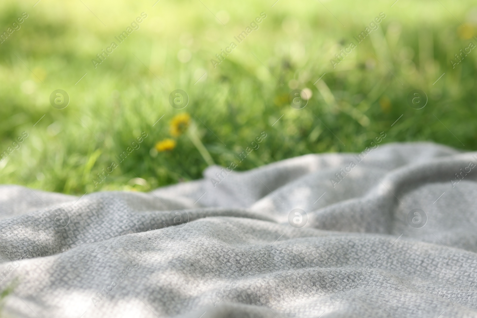 Light grey blanket for picnic on green grass outdoors, closeup Photo of Light grey blanket for picnic on green grass outdoors, closeup