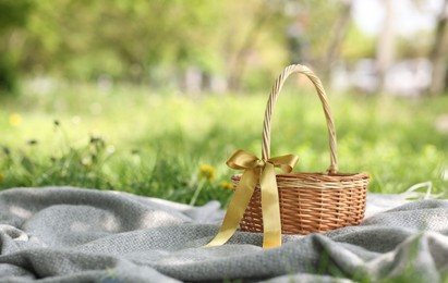 Photo of Wicker basket on blanket outdoors. Space for text