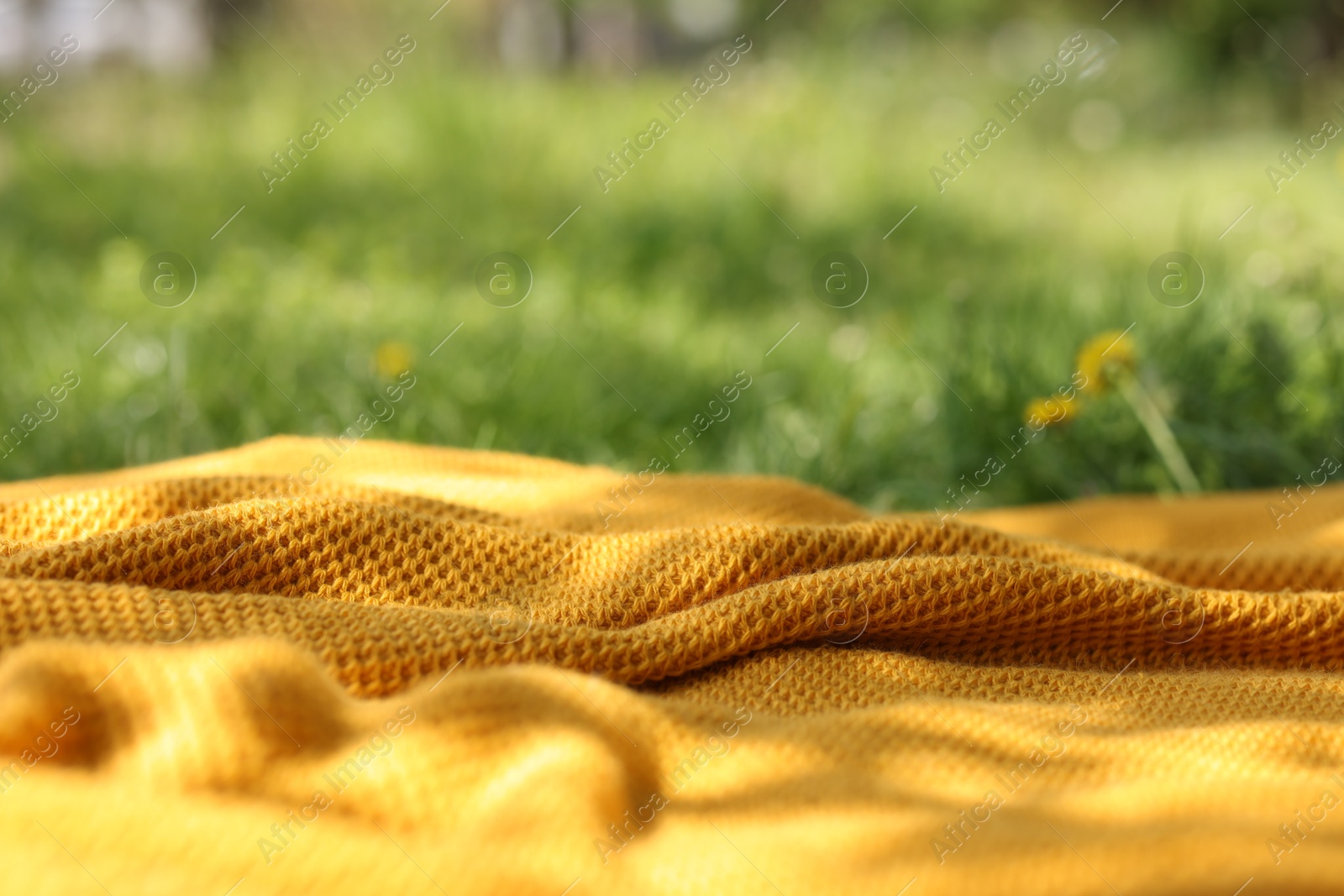 Orange blanket for picnic on green grass outdoors, closeup Photo of Orange blanket for picnic on green grass outdoors, closeup