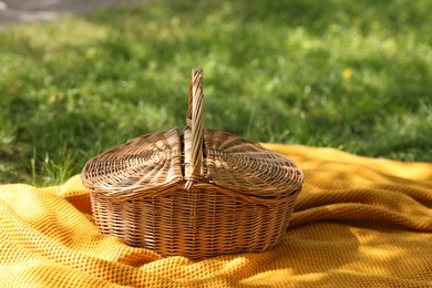 Photo of Wicker basket and blanket on green grass outdoors