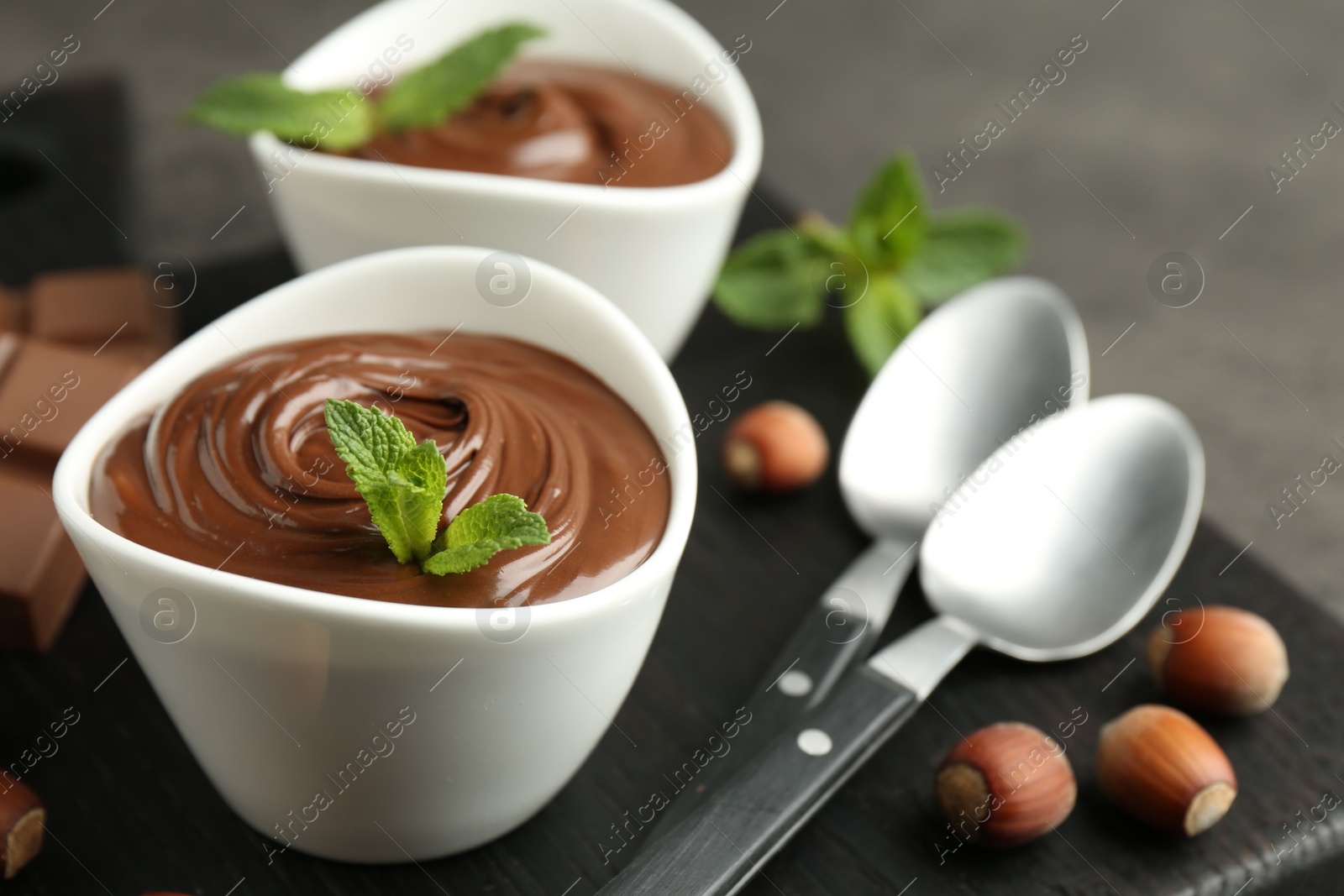 Photo of Tasty chocolate spread, pieces, mint and hazelnuts on table, closeup