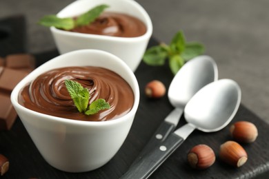Photo of Tasty chocolate spread, pieces, mint and hazelnuts on table, closeup