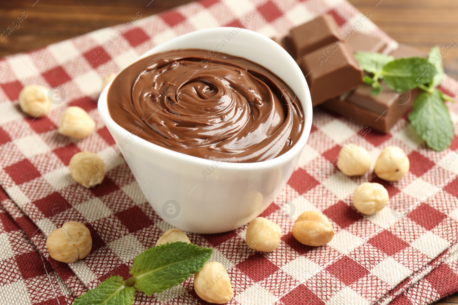 Tasty chocolate spread, pieces, mint and hazelnuts on table, closeup Photo of Tasty chocolate spread, pieces, mint and hazelnuts on table, closeup