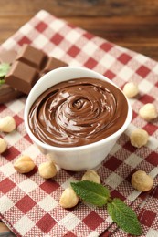 Photo of Tasty chocolate spread, pieces, mint and hazelnuts on table, closeup