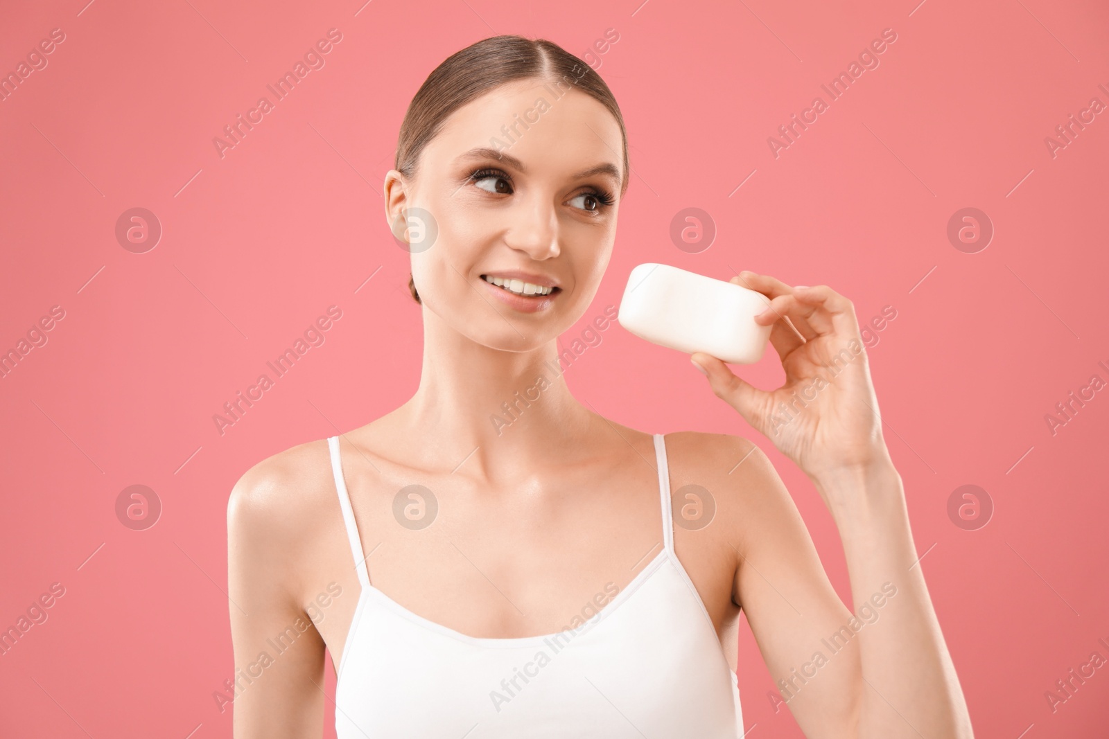 Smiling woman with soap bar on pink background Photo of Smiling woman with soap bar on pink background