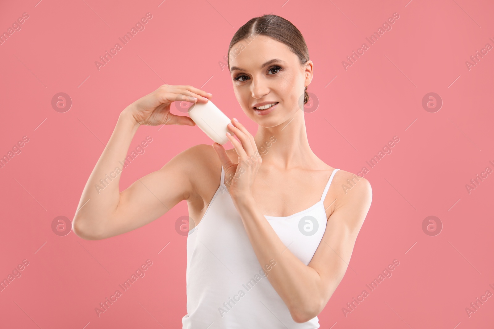 Smiling woman with soap bar on pink background Photo of Smiling woman with soap bar on pink background