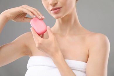 Photo of Woman with soap bar on grey background, closeup