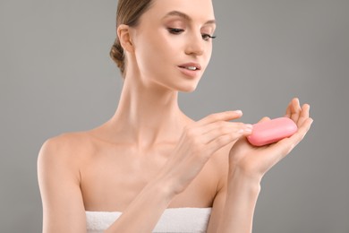 Photo of Beautiful woman with soap bar on grey background