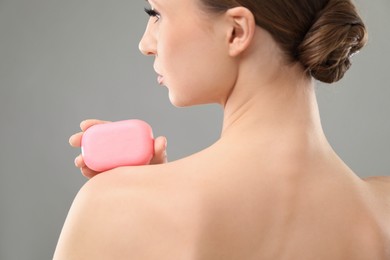 Photo of Woman with soap bar on grey background, closeup