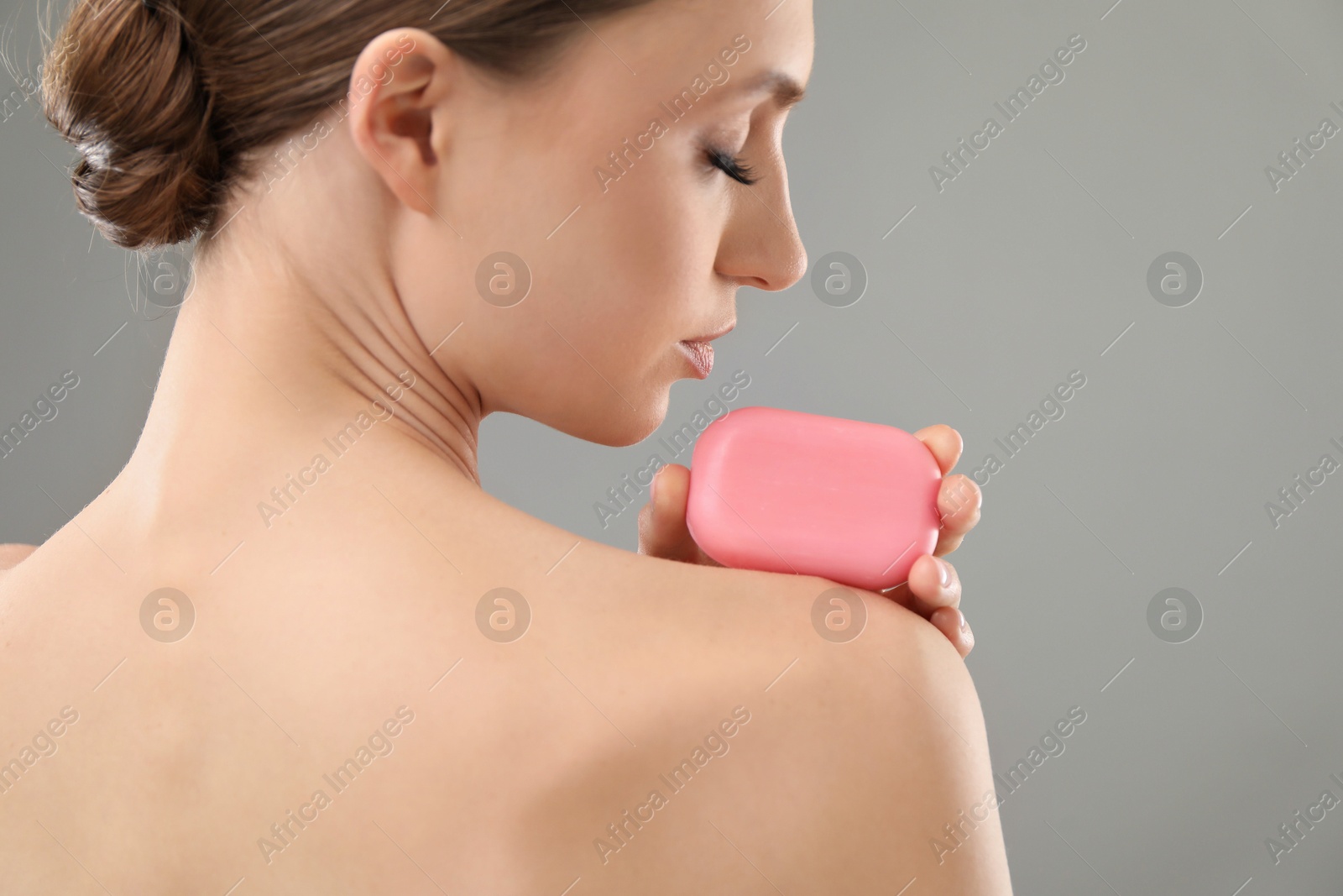 Woman with soap bar on grey background, closeup Photo of Woman with soap bar on grey background, closeup