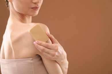 Photo of Woman with soap bar on brown background, closeup. Space for text