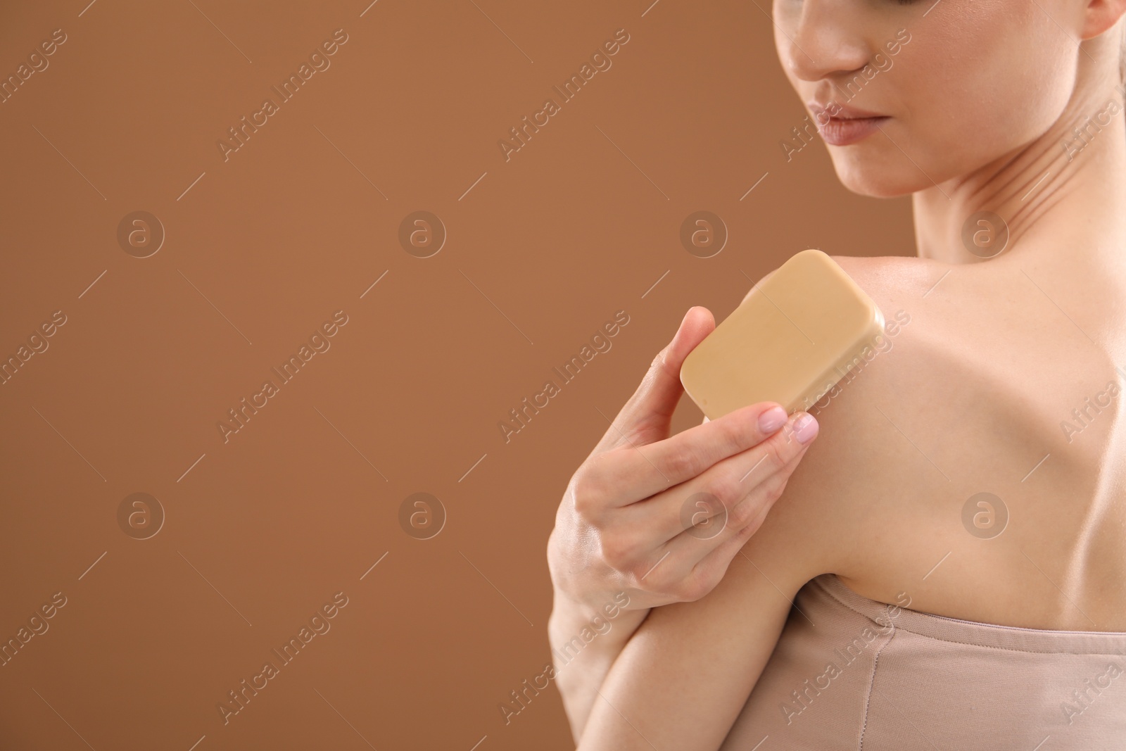 Woman with soap bar on brown background, closeup. Space for text Photo of Woman with soap bar on brown background, closeup. Space for text