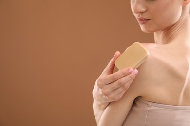 Photo of Woman with soap bar on brown background, closeup. Space for text